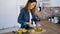 Pretty young woman cutting an apple for preparing detox beverage in the kitchen at home.