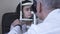 Pretty young woman do eye test at clinic sitting in front of doctor in white medical coat looking in eye test machine