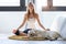 Pretty young woman doing yoga while her dog lying on the floor at home