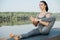 Pretty young woman doing yoga outdoors in a beautiful spot on a riverside