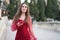 Pretty young woman, in an elegant maroon red dress walking with her smartphone