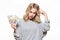 Pretty young woman in grey sweater holding bunch of Euro banknotes, scratching her head thinking, isolated on white.