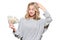 Pretty young woman in grey sweater holding bunch of Euro banknotes, scratching her head thinking, isolated on white background.