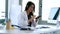 Pretty young woman gynaecologist using her mobile phone before starting consultation in the clinic.