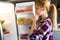 Pretty young woman hesitant to eat in front of the fridge in the kitchen.