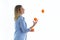 Pretty young woman juggling with oranges over white background