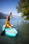 Pretty, young woman paddling on a paddle board on a lake