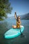 Pretty, young woman paddling on a paddle board on a lake