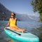 Pretty, young woman paddling on a paddle board on a lake