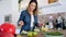 Pretty young woman preparing a fruit plate and eating a slice of banana in the kitchen at home.