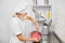 Pretty young woman, professional confectioner, preparing red cream or batter in stainless steel bowl, mixing it with