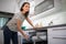 Pretty, young woman putting dishes in the dishwasher