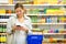 Pretty, young woman with a shopping basket buying groceries