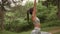 Pretty young woman stretching and breathing fresh air in middle of forest while exercising