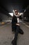 Pretty young woman in stylish clothes in vintage silk scarf on head in dark fashionable sunglasses in trendy black outerwear poses