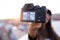 Pretty young woman taking a selfie with camera while sitting on the rooftop