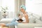 Pretty young woman with towel on head reading book and drinking coffee in room