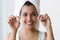 Pretty young woman using dental floss in a home bathroom.