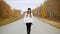 A pretty young woman walking in the middle of the road. Autumn