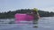 Pretty young woman wearing bikini, yellow hat and purple sunglasses swimming with pink inflatable ring in infinity rooftop pool.