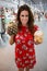 A pretty young woman wearing a red flowered dress, holding in her hands a pineapple and coconut natural drinks