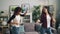 Pretty young women Asian and African American are dancing at home listening to music and having fun together relaxing in