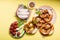 Pretzels, white bavarian sausages and vegetables on yellow background, german traditional food, oktoberfest