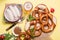 Pretzels, white bavarian sausages and vegetables on yellow background, german traditional food, oktoberfest