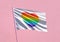 Pride rainbow heart flag waving on a pink wall background for LGBTQIA+ Pride month, sexuality freedom, love diversity celebration