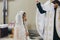 Priest blessing with holy water stylish bride in kerchief at altar during holy matrimony in church. Wedding ceremony in cathedral