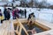 Priest consecrates the ice hole. Man bathes into cold water of ice-hole