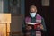 Priest in mask reading the Bible