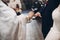 Priest putting on golden wedding rings on groom hand in church d