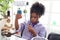 Primary school African curly hair girl does chemistry science experiment in laboratory, cute scientist kid holds chemical test