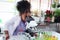 Primary school African curly hair girl looks under microscope, does science experiment in laboratory, cute scientist kid use lab