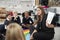 Primary school children sitting on the floor in the classroom with their teacher holding up a book to show them, selective focus