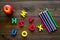 Primary school concept. Letters of english alphabet, apple and color pencils on dark wooden background top view