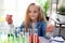 Primary school girl with long blonde hair doing chemistry science experiment in laboratory, cute scientist kid with colorful test