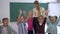 Primary school, group of children fun jumping and waving hands near to the teacher on background of the board