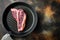 Prime cut tender raw t bone steak for a BBQ, in frying cast iron pan, on old dark rustic background, top view flat lay, with copy