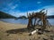 Primitive looking stick hut on beach of Lake Tahoe\'s Emerald Bay with a sailboat in background on the lake