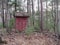 Primitive Red Outhouse in a Forest
