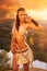 Primitive woman on the rock at the sunset. Amazon woman