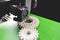 print head, bright green print bed and white helical gears with visible infill and layer. opblique view on process of 3D-printing