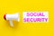 Printed words social security near megaphone on yellow background with computer keyboard top view space for text