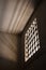 Prison cell with light shining through a barred window