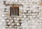 Prison cell window with wooden bars in a white brick wall