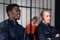 Prison guards smile as they stand with batons near cells with dangerous criminals. Multi-racial portrait.