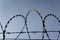 Prison wall barbed wire fence with blue sky in background