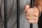 Prisoner behind bars.hand of prisoner on steel jail bars.Man under arrested by policeman because illegal behaviour